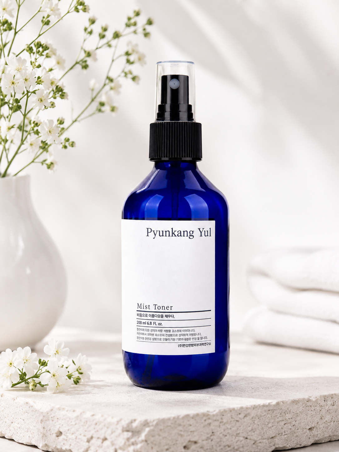 Pyunkang Yul Mist Toner 100ml on a white surface with flowers in the background